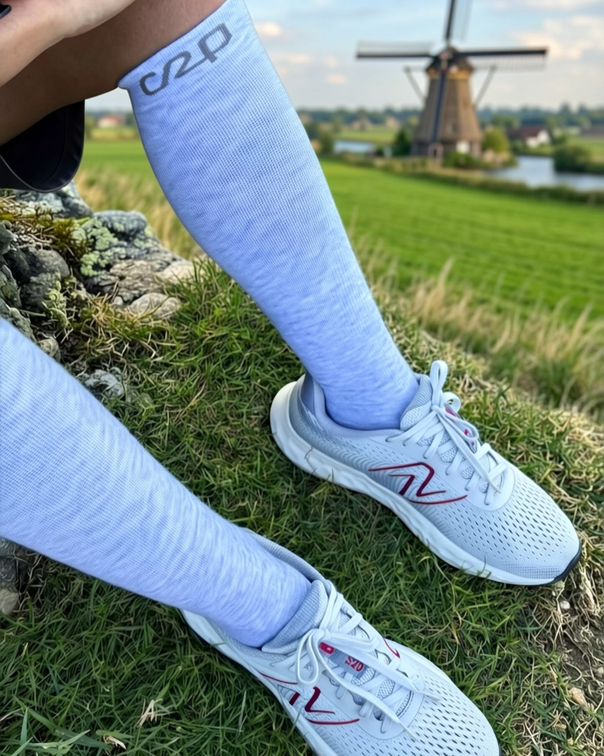 Light blue merino knee-high compression socks with trainers by a Dutch windmill